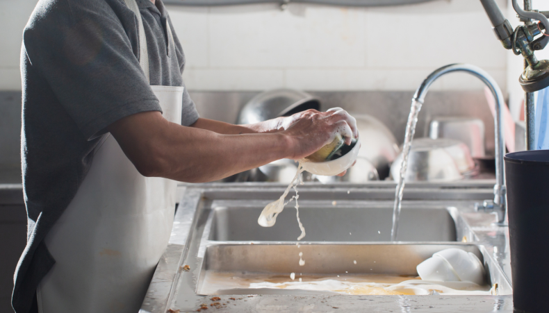 Man washing dishes in a restaurant kitchen