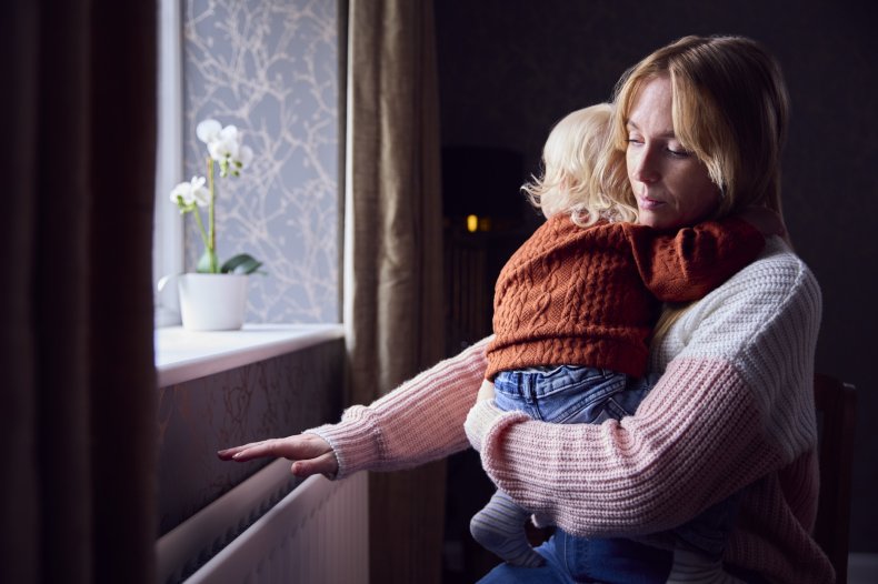 Child hugging upset woman near a window.