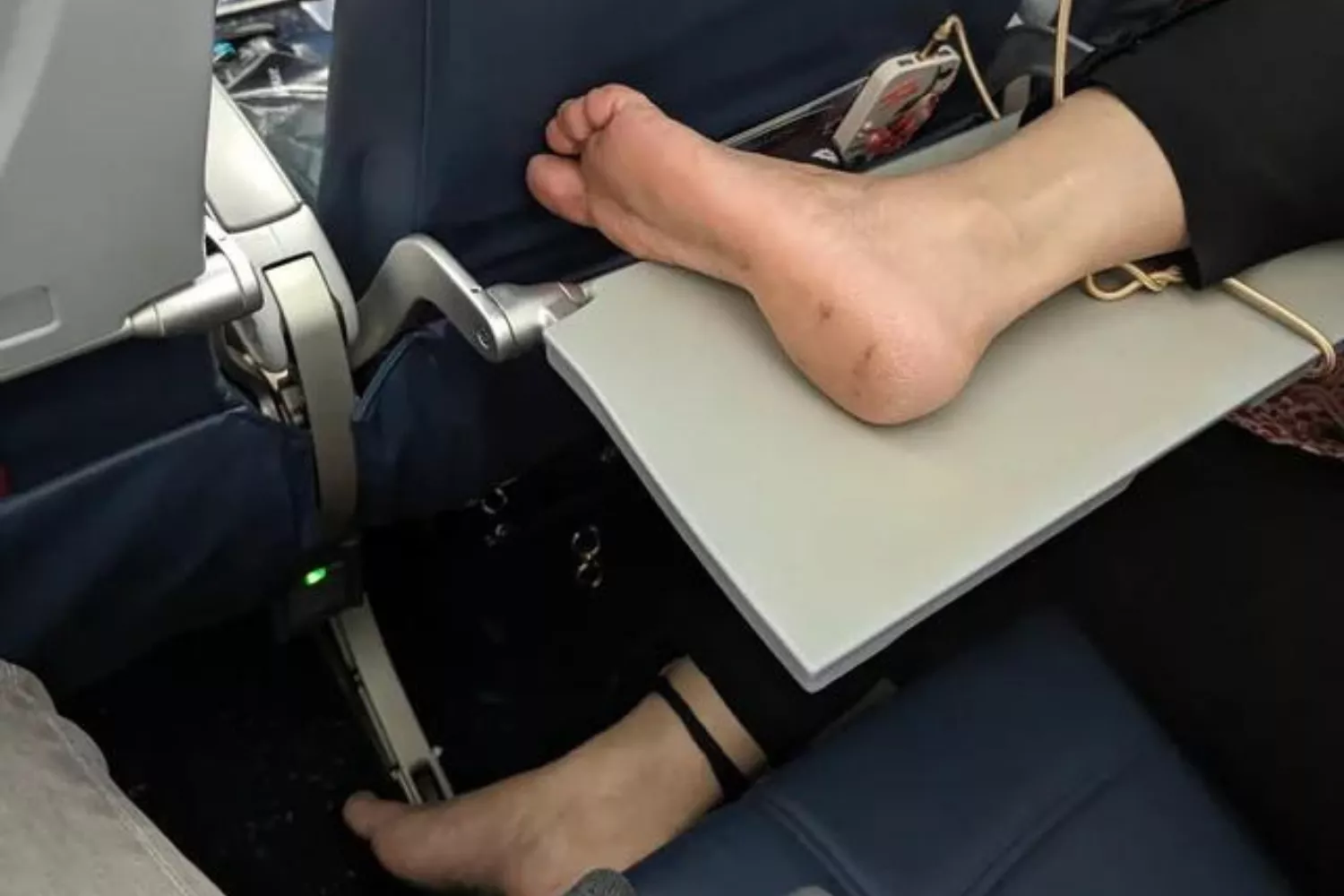 Airplane Passenger Puts Bare Feet On Tray Table - Travel Noire