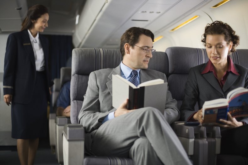 Two passengers looking at books on plane.