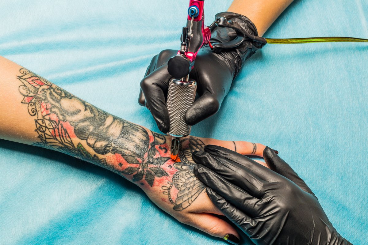 tattoo artist inking a woman's arm