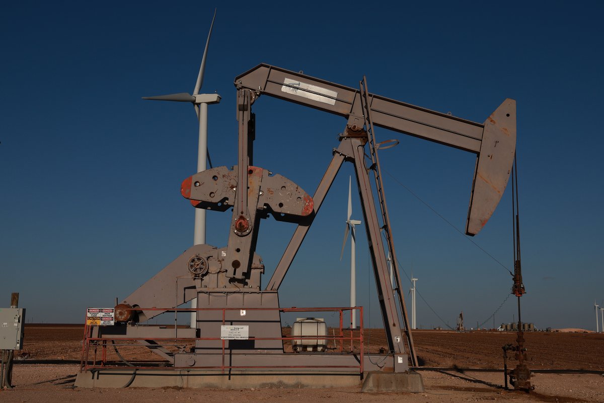  An oil pumpjack works near wind turbines 