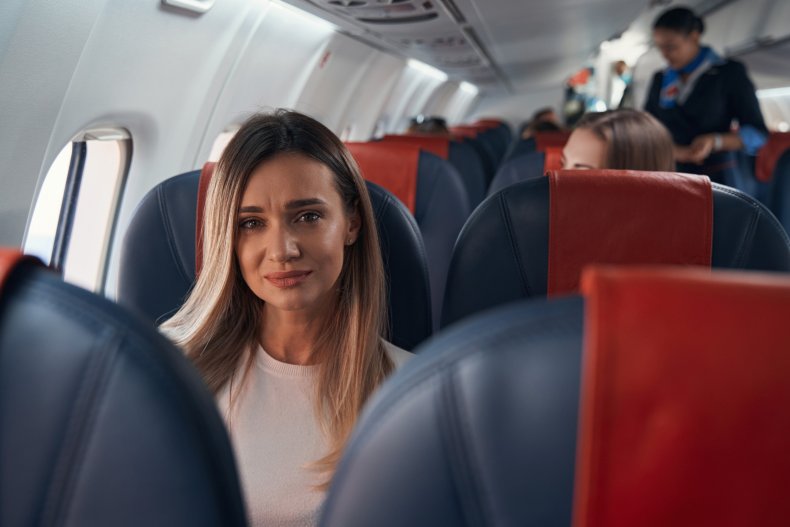 Woman looking distraught, sitting on plane.
