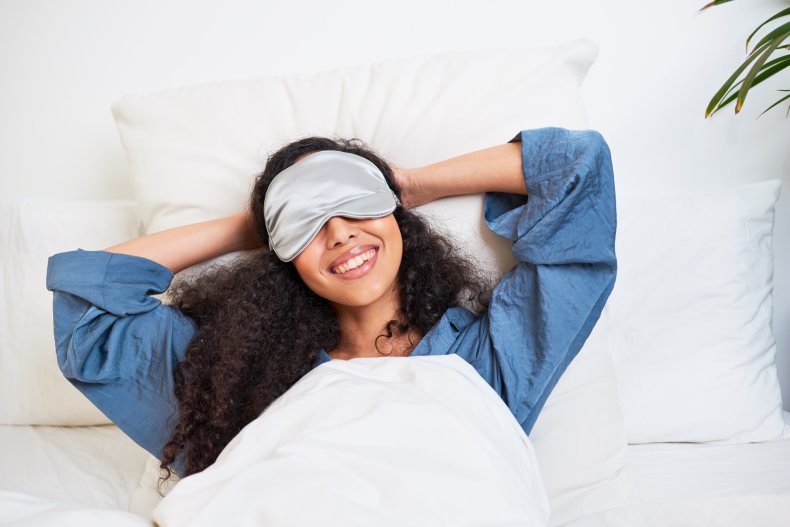Femme portant un masque pour les yeux au lit.
