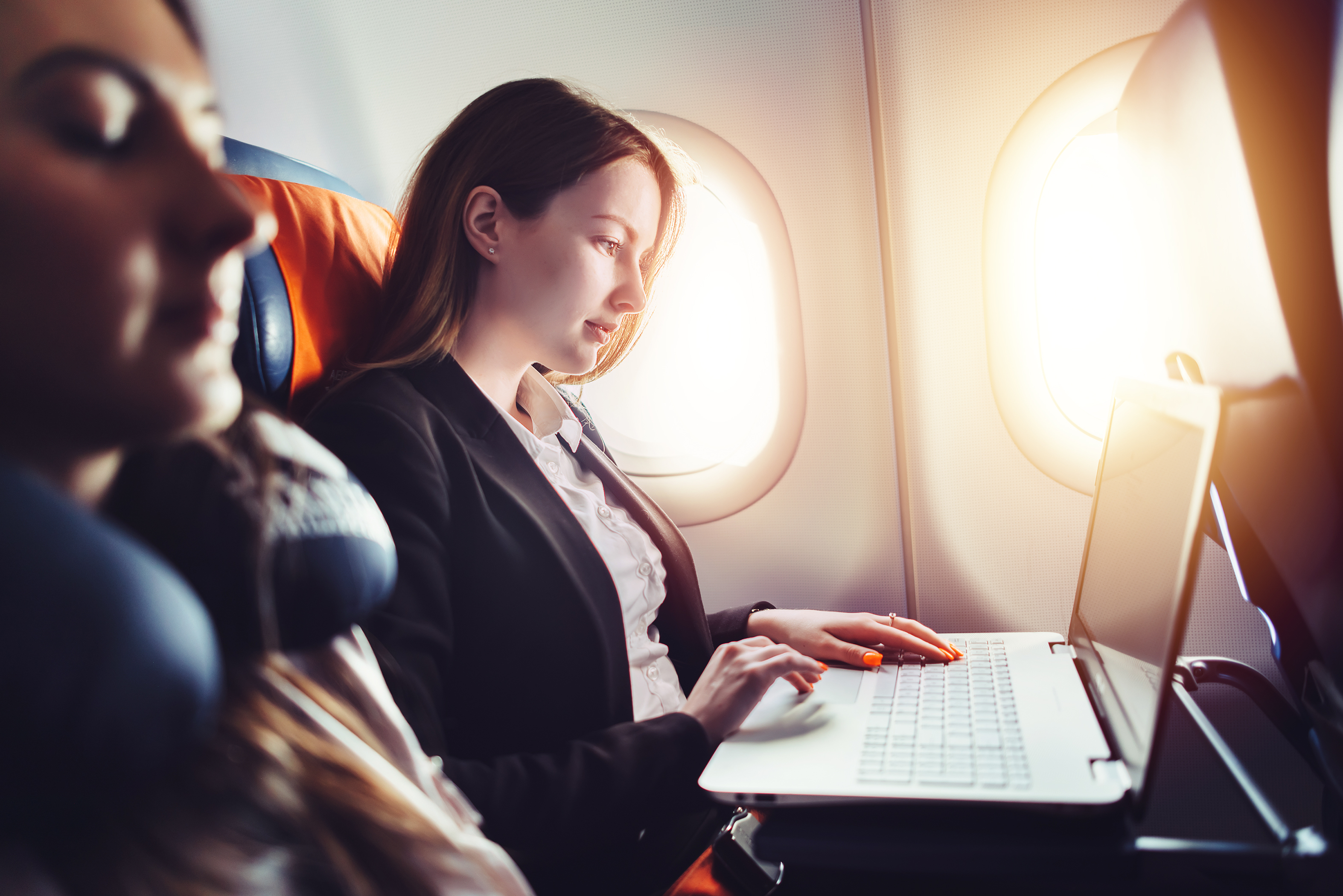 Будущее командировок. Девушка в самолете. Успешная женщина. Девушка с ноутбуком в самолете. Путешествие на самолете.