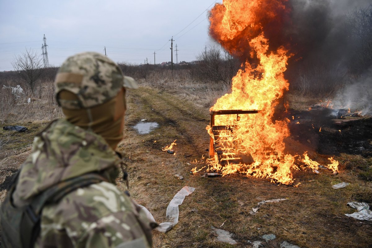 A Ukrainian soldier looks at flames 