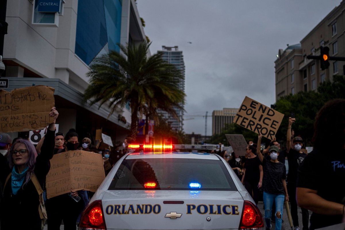 Protesters march past a police car 