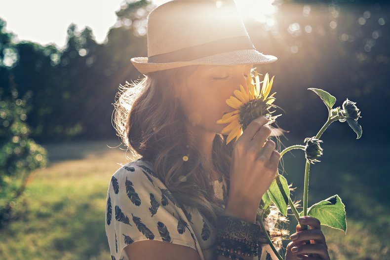 Woman smelling sunflower under the sun.