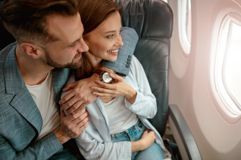 An affectionate couple seated on plane.