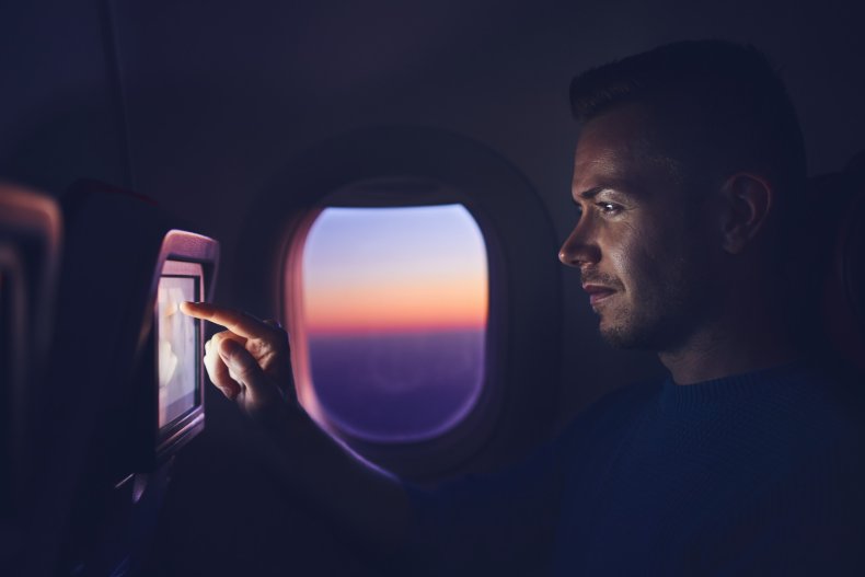 Man using television screen on night flight.