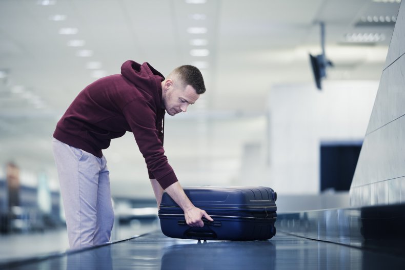 Man picking up luggage from baggage belt.