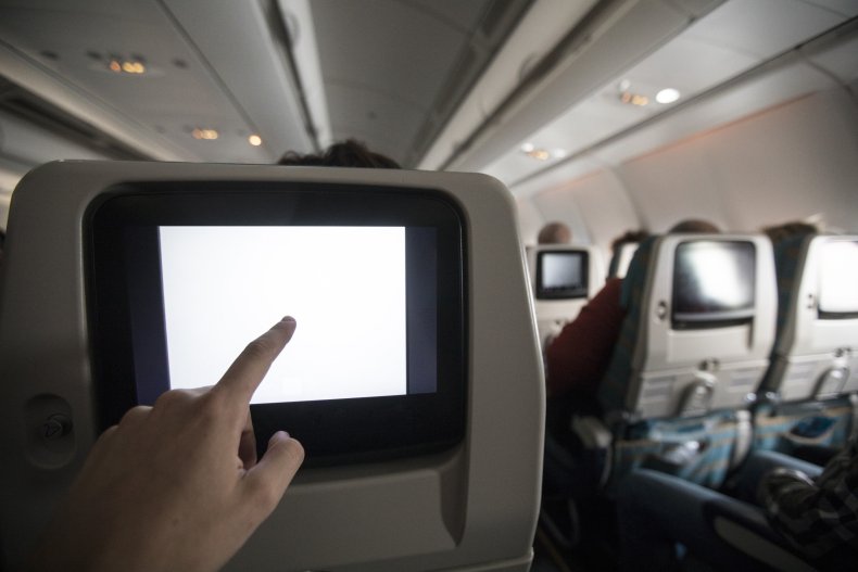 Plane passenger pointing at in-flight television screen.