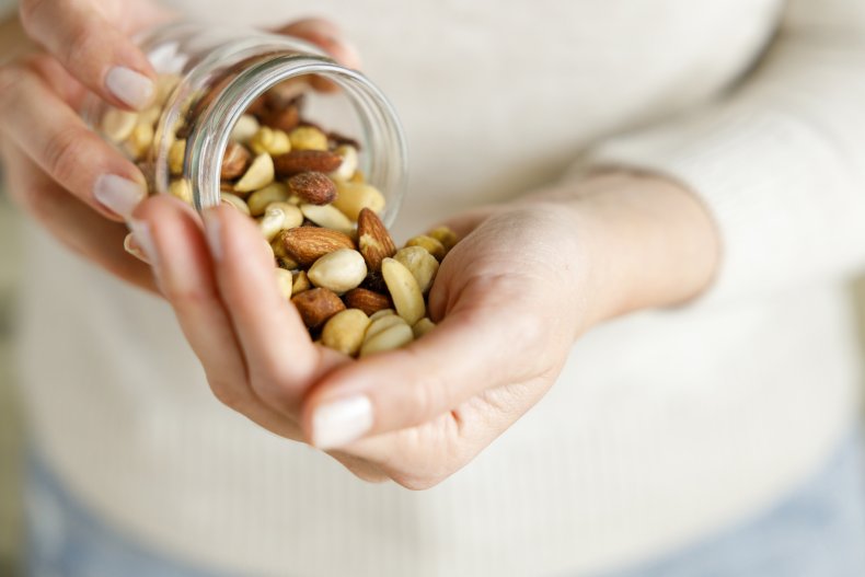 Woman pouring jar of nuts into hand