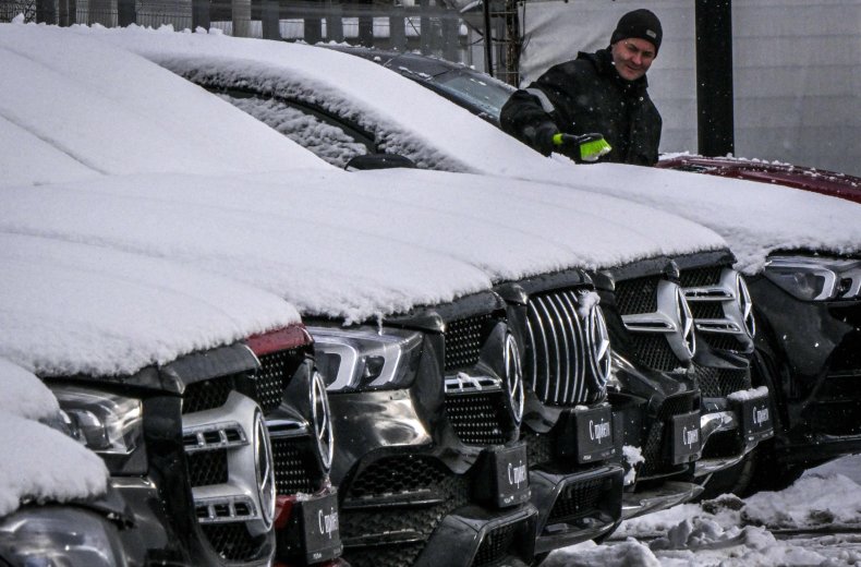 L'uomo spazza via la neve dalle auto Mercedes Mosca