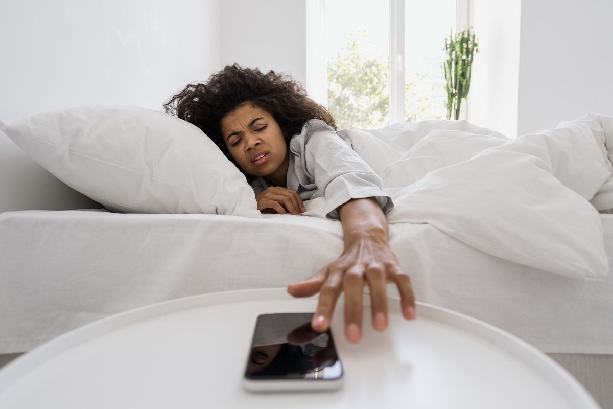 Woman snoozing phone alarm