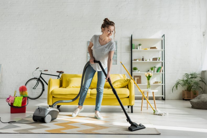 A woman vacuums the floor in a house. 