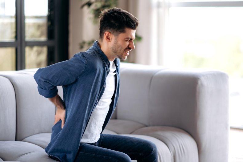 Man feels back pain on sofa.