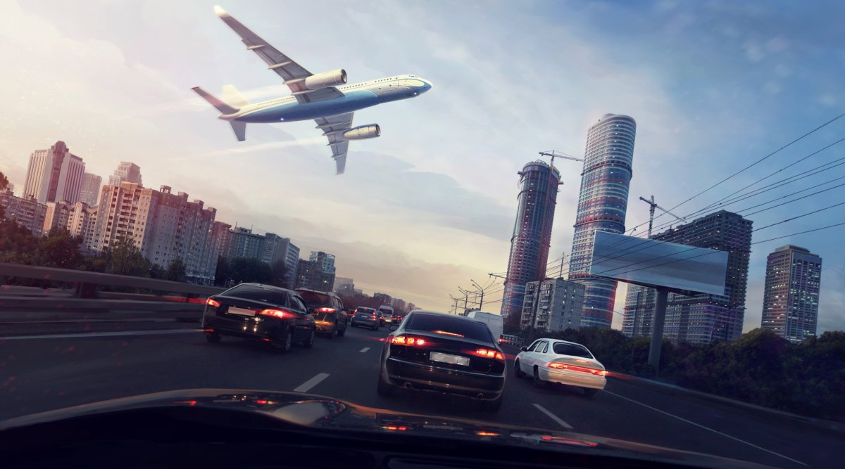 Plane flying over motorway with cars.