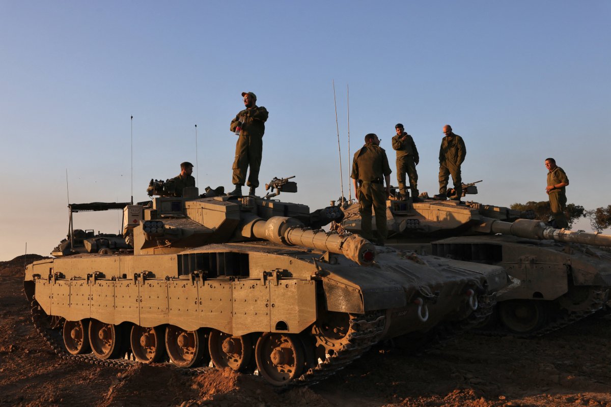 Israeli soldiers stand on tanks deployed on