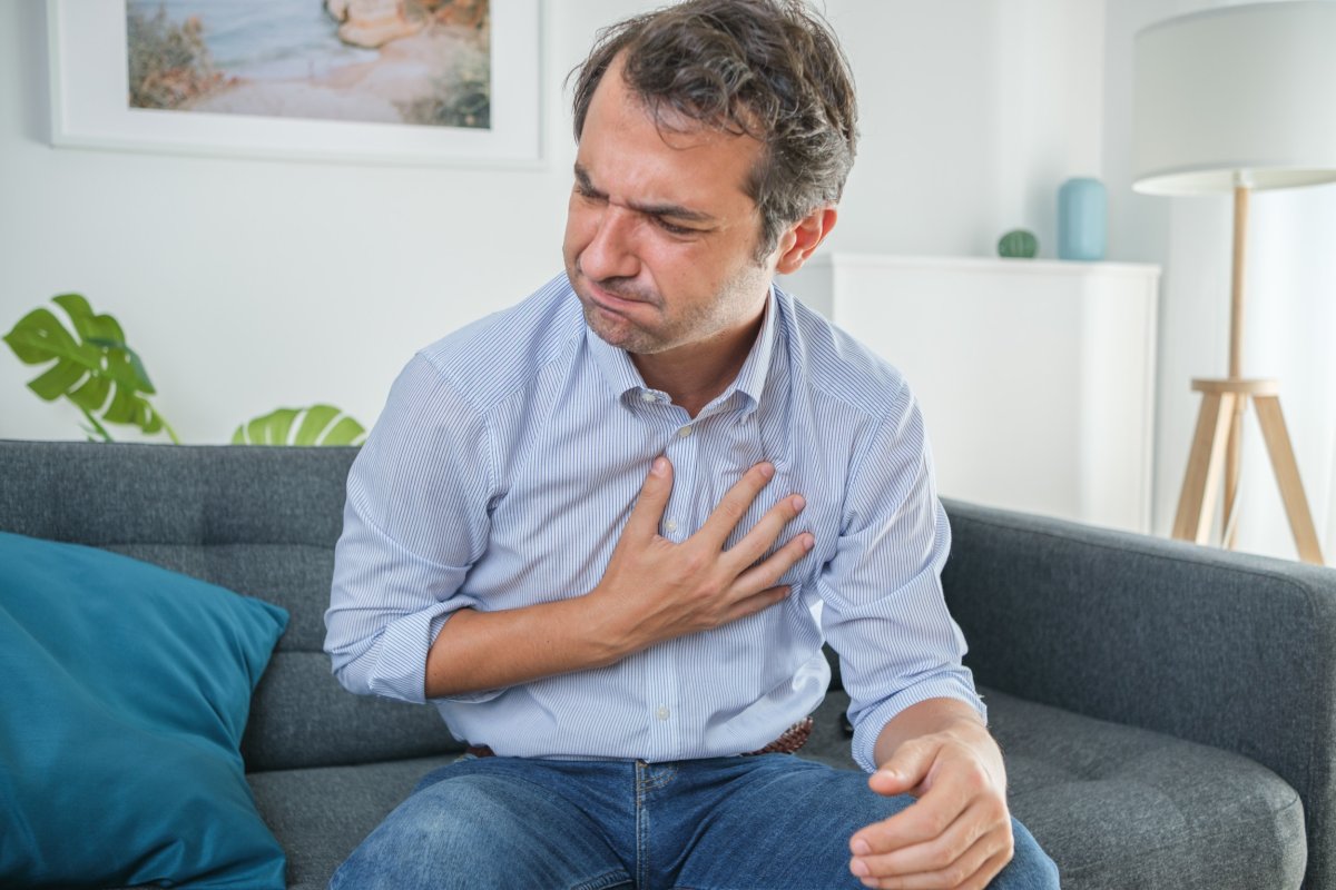 Man feeling heartburn on a couch.