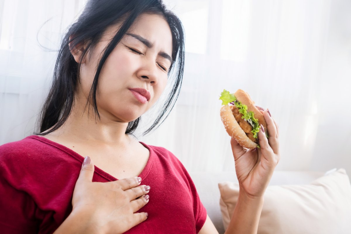 Woman with hand on chest, holding burger.