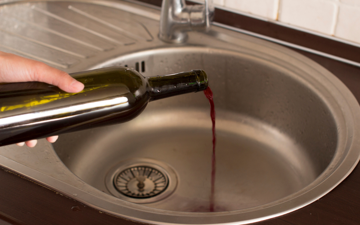 A bottle of red wine poured away.