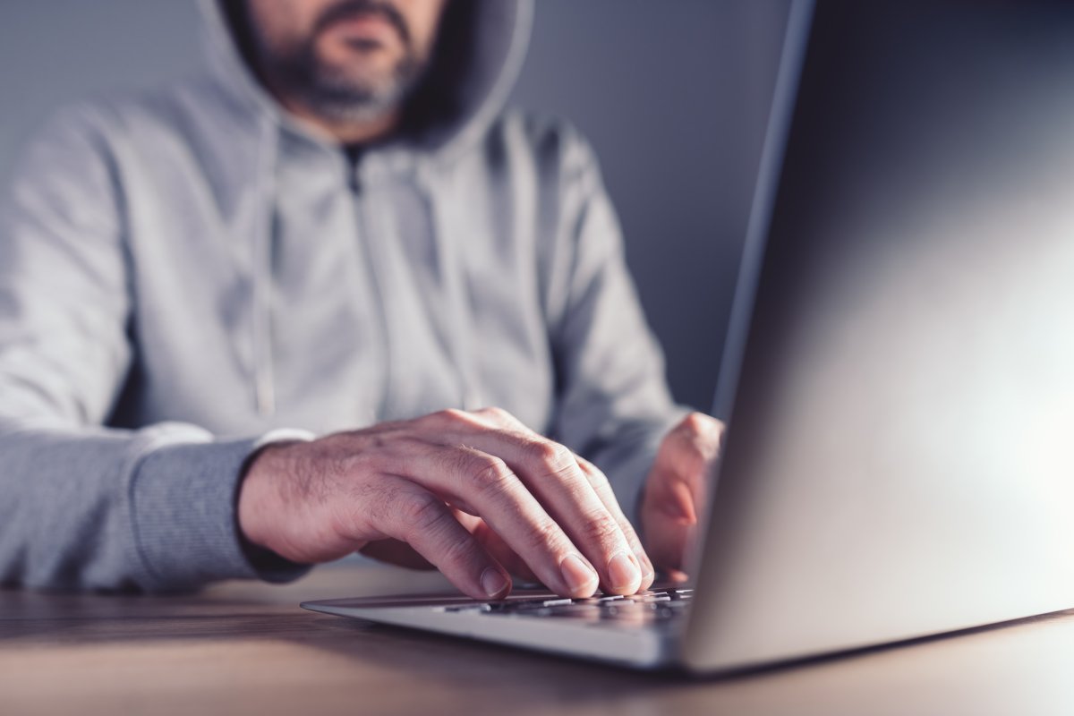 A hooded man uses a laptop