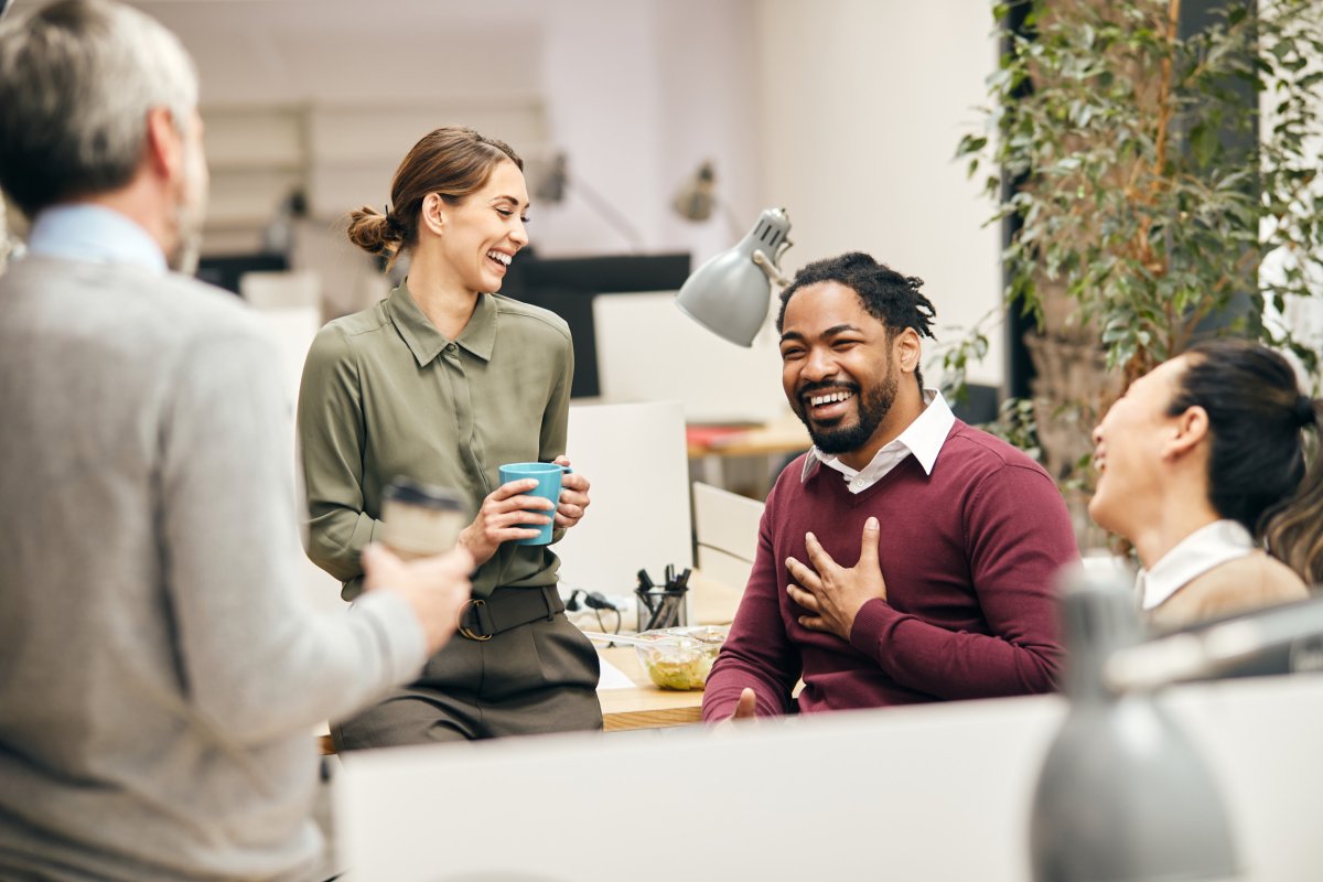 Workers smiling around office desk.