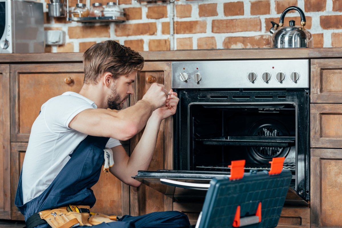 man repairing broken appliance getty