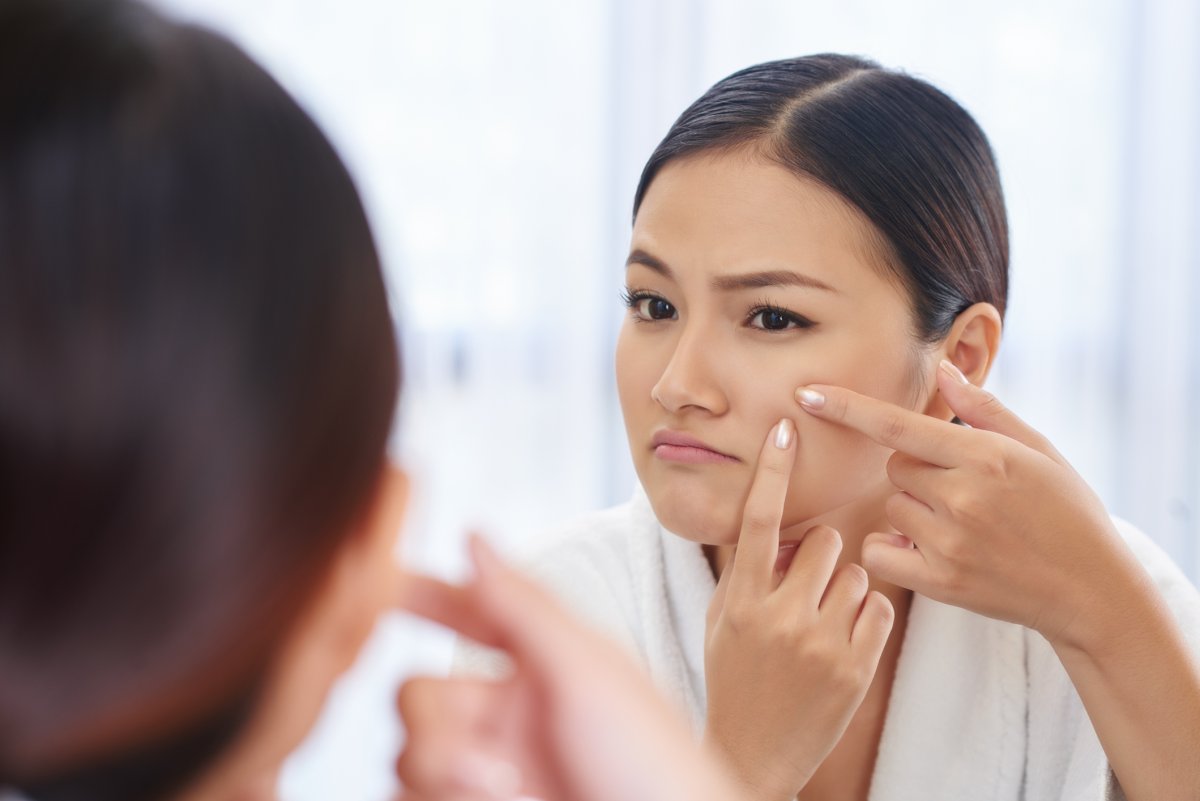 Woman Squeezing Pimple In Mirror