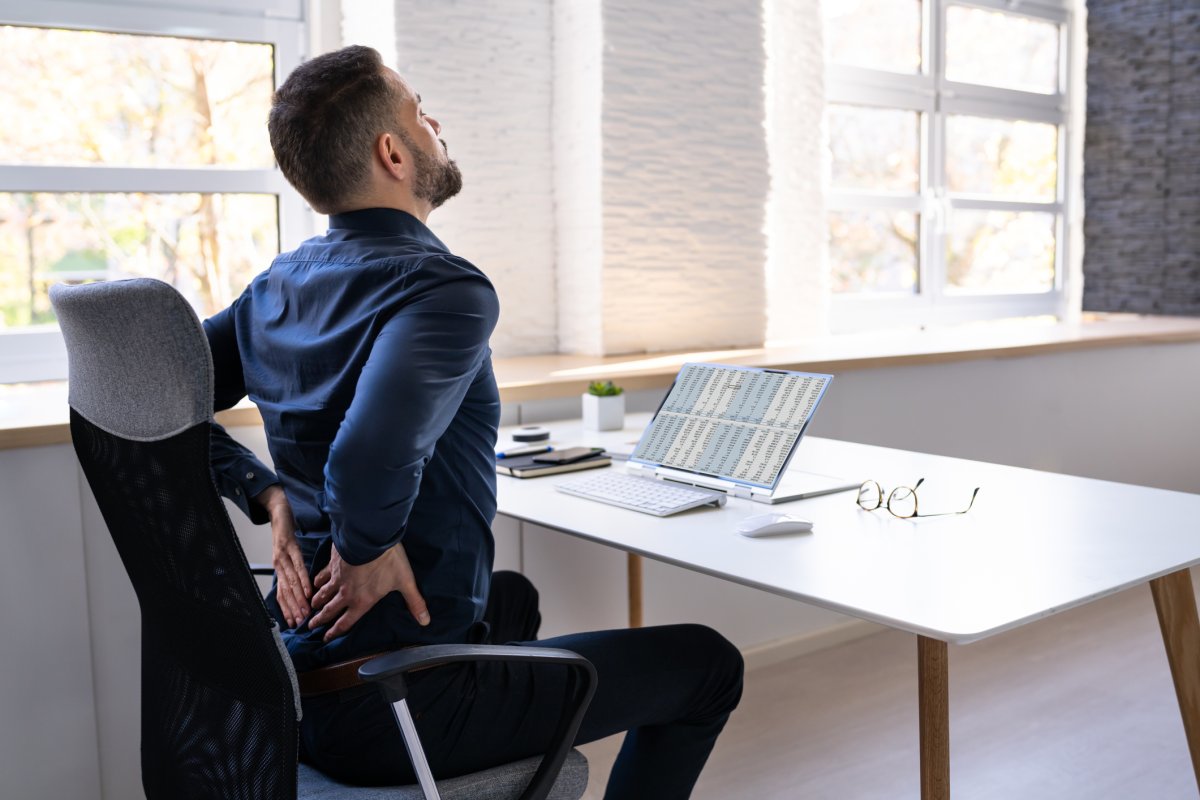 Man Sat At Desk With Back Pain