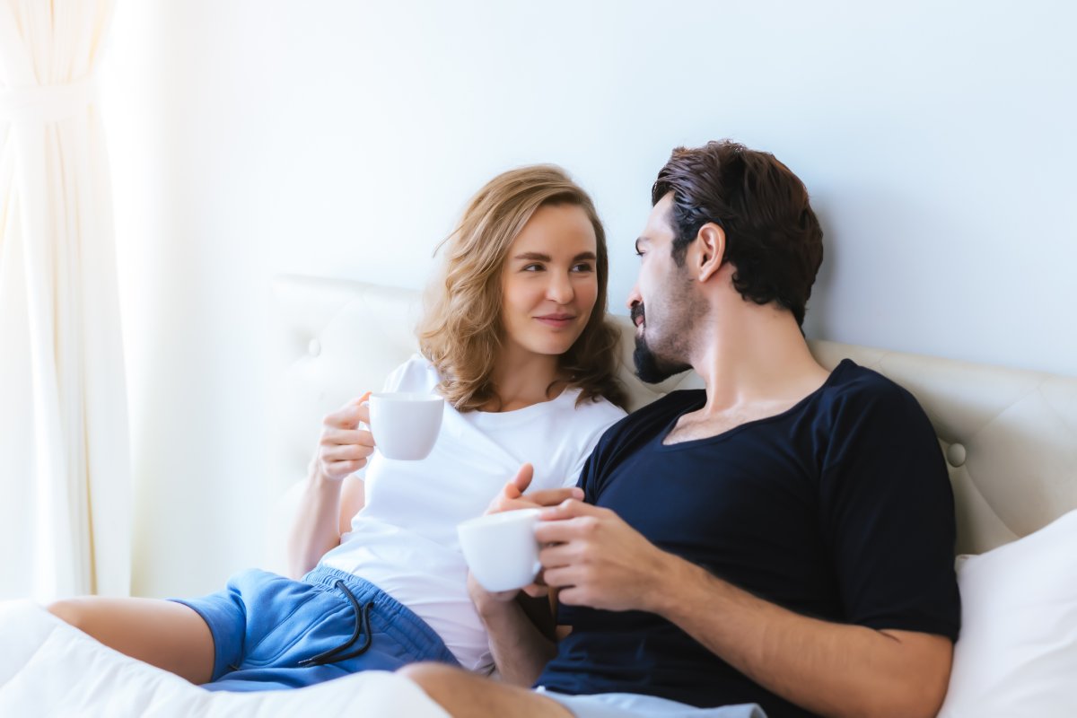 A man and woman talk in bed