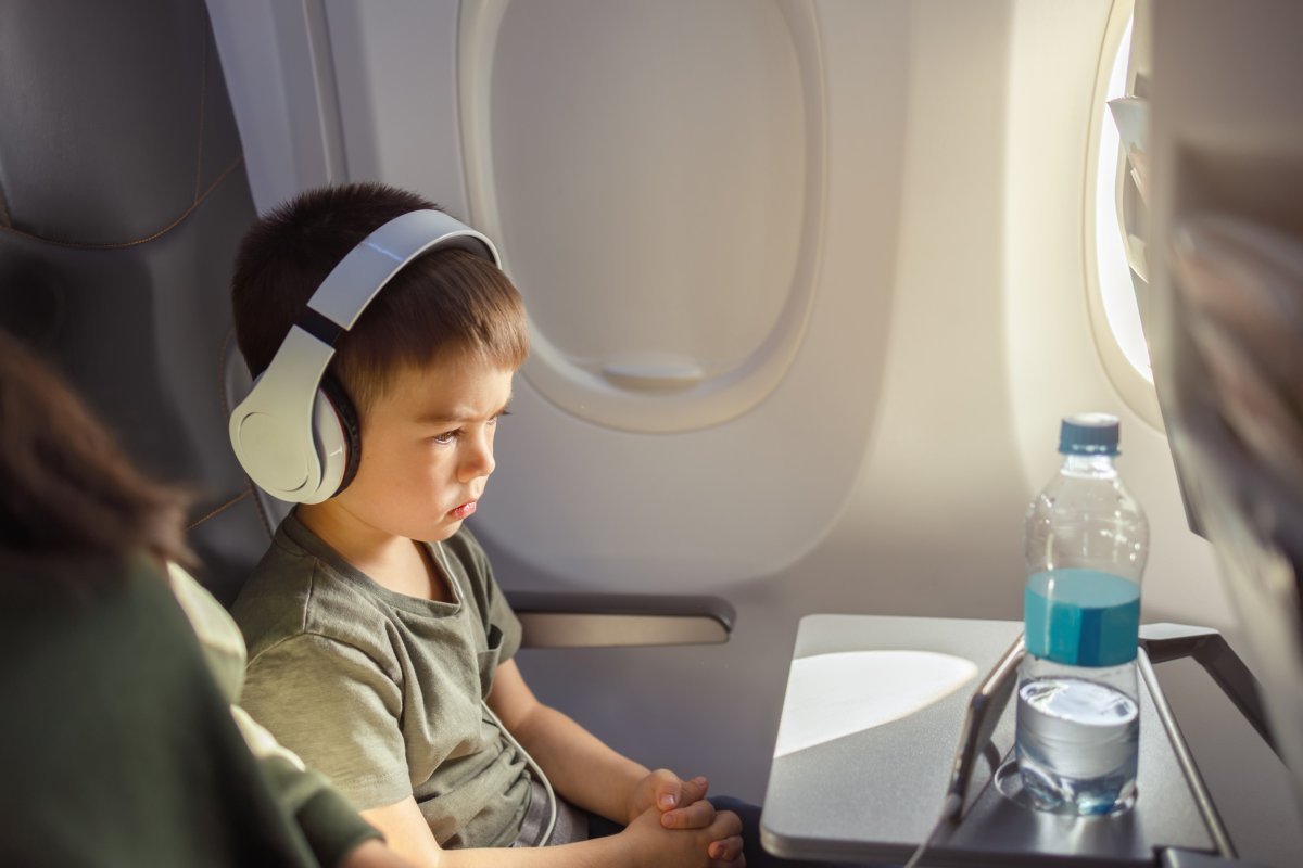 Boy staring at seatback on plane.