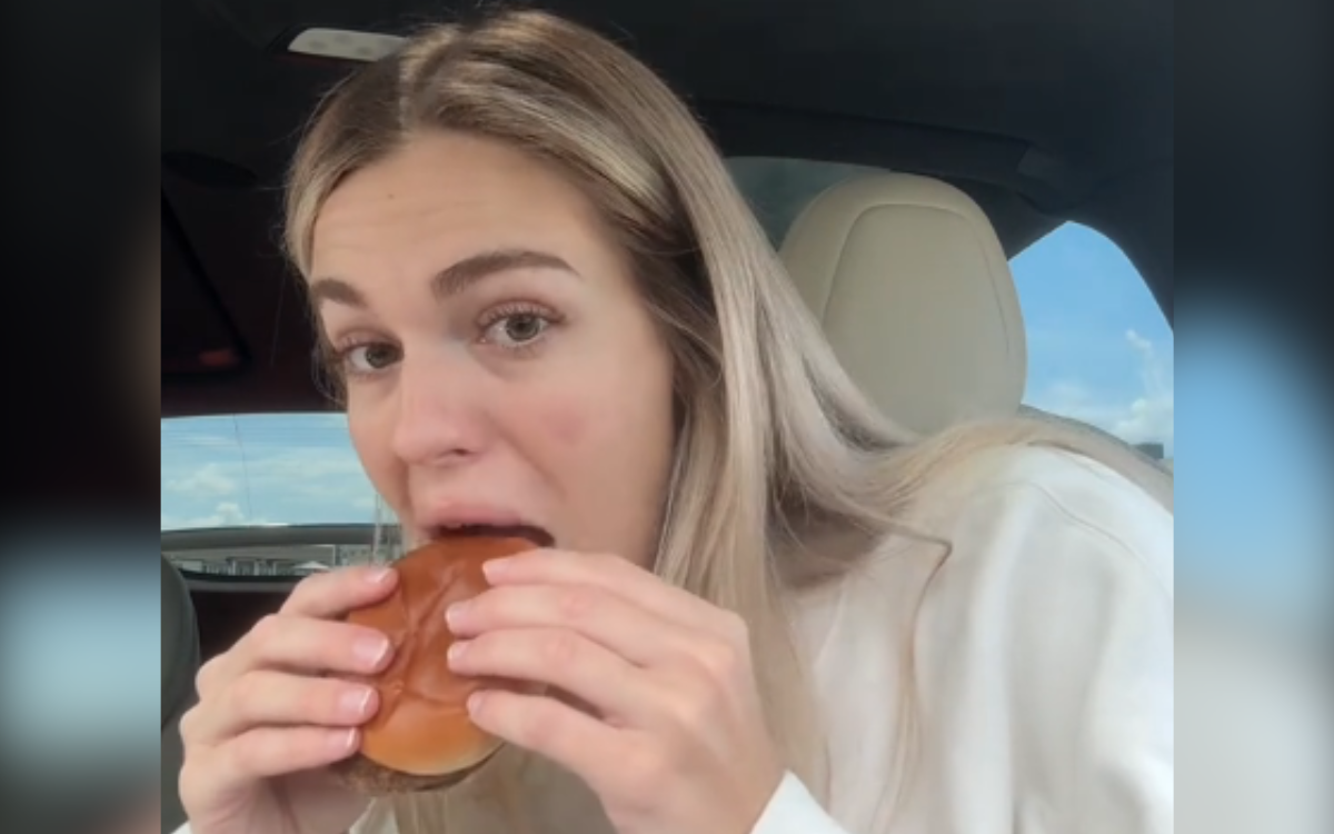 A pregnant woman eating a McDonald's hamburger.