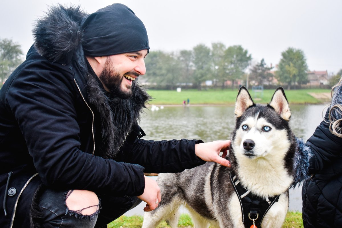 Man smiling next to husky dog.
