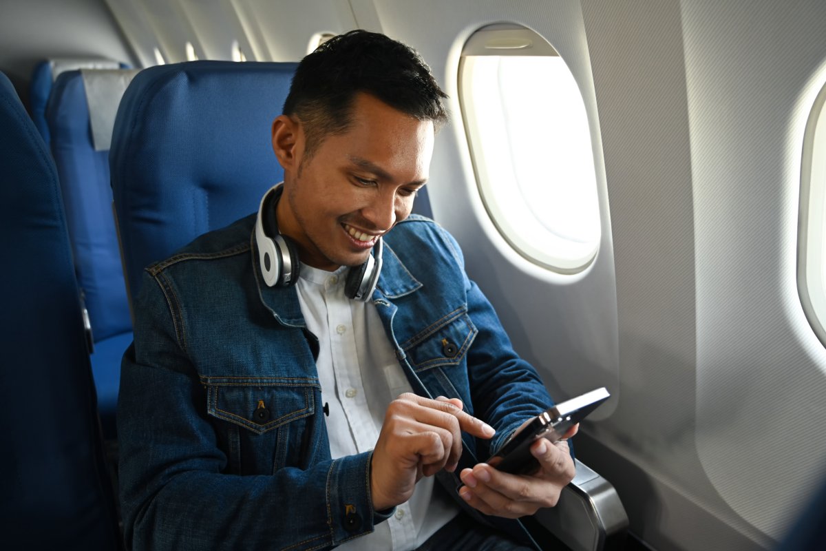 Plane passenger smiling while looking at phone.