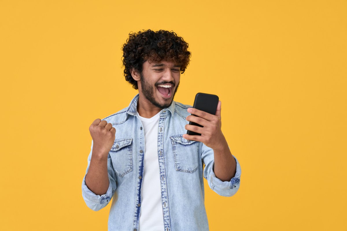 Man Excited Holding Cell Phone Yellow Background