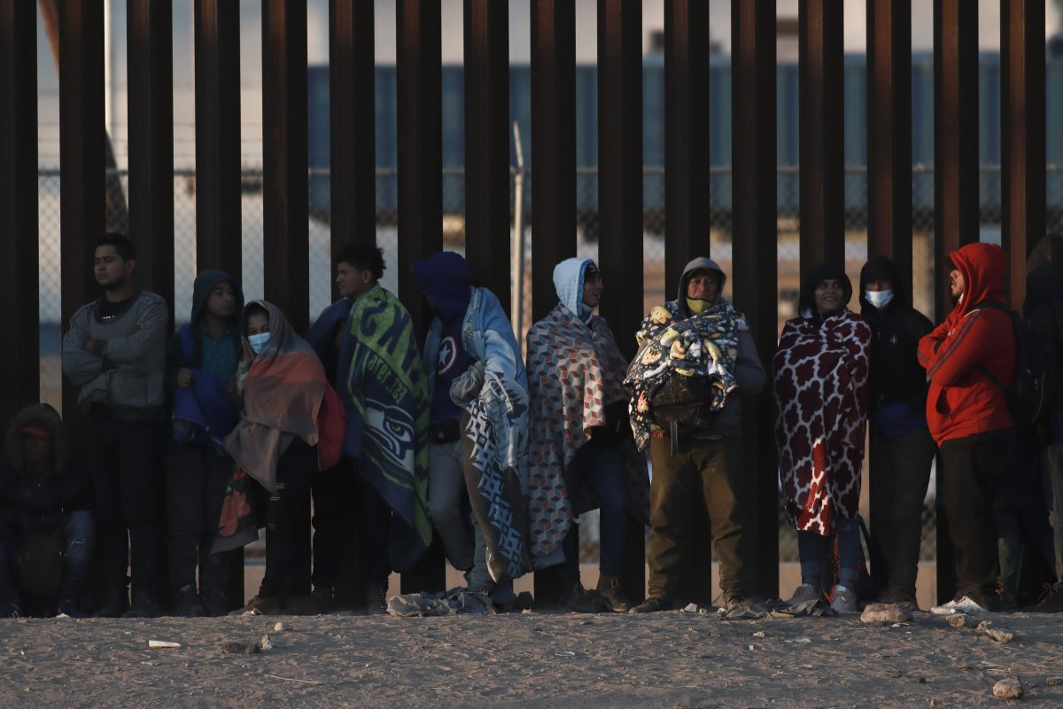 Migrantes se reúnen junto al muro fronterizo