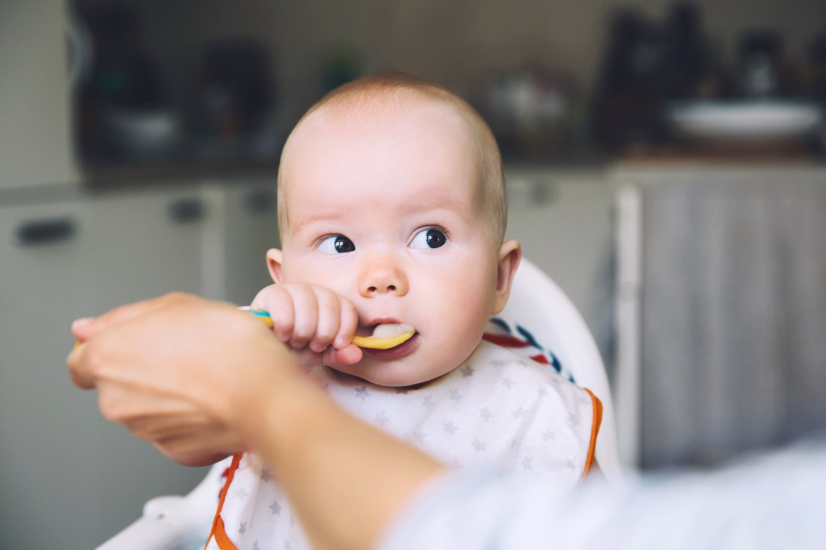 Messy smiling baby eating with a spoon