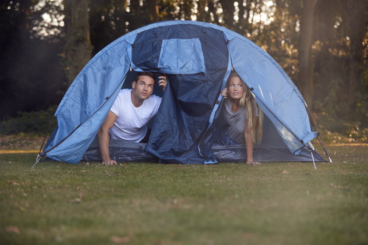 Couple inside a tent in forest setting.