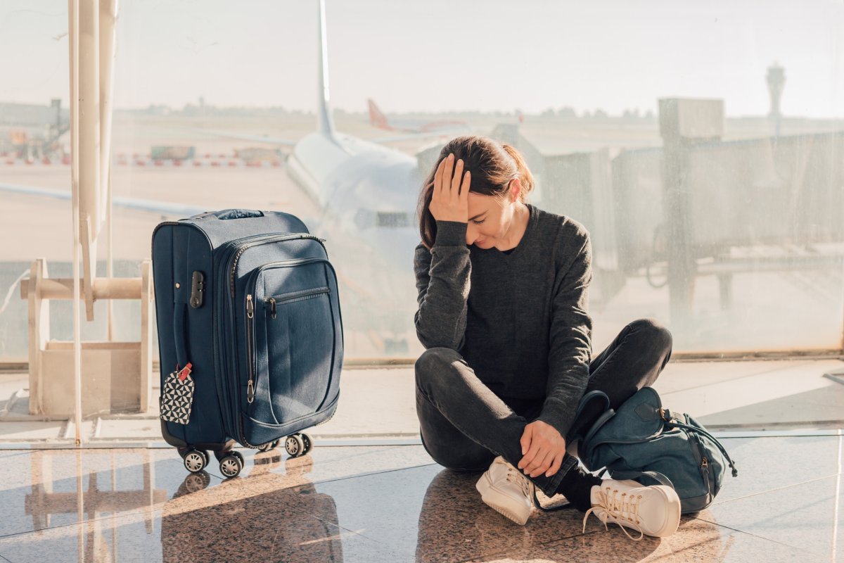Woman next to suitcase upset at airport.