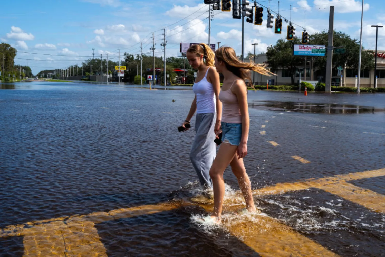 https://d.newsweek.com/en/full/2495234/women-walk-through-milton-floods.webp