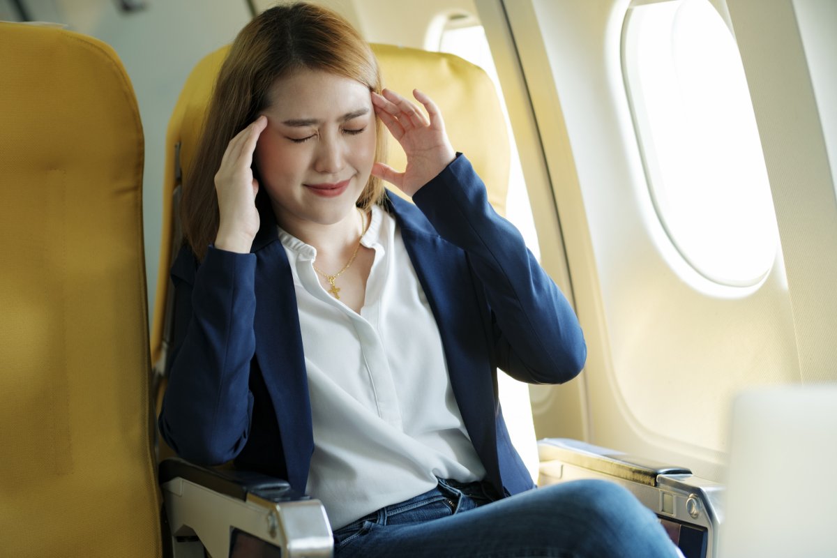 Woman with hands on head on plane.