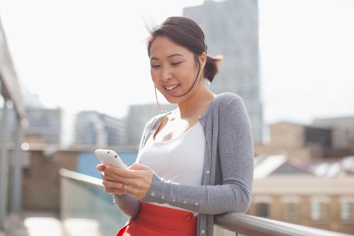 Smiling businesswoman sending text messages using cell phone 