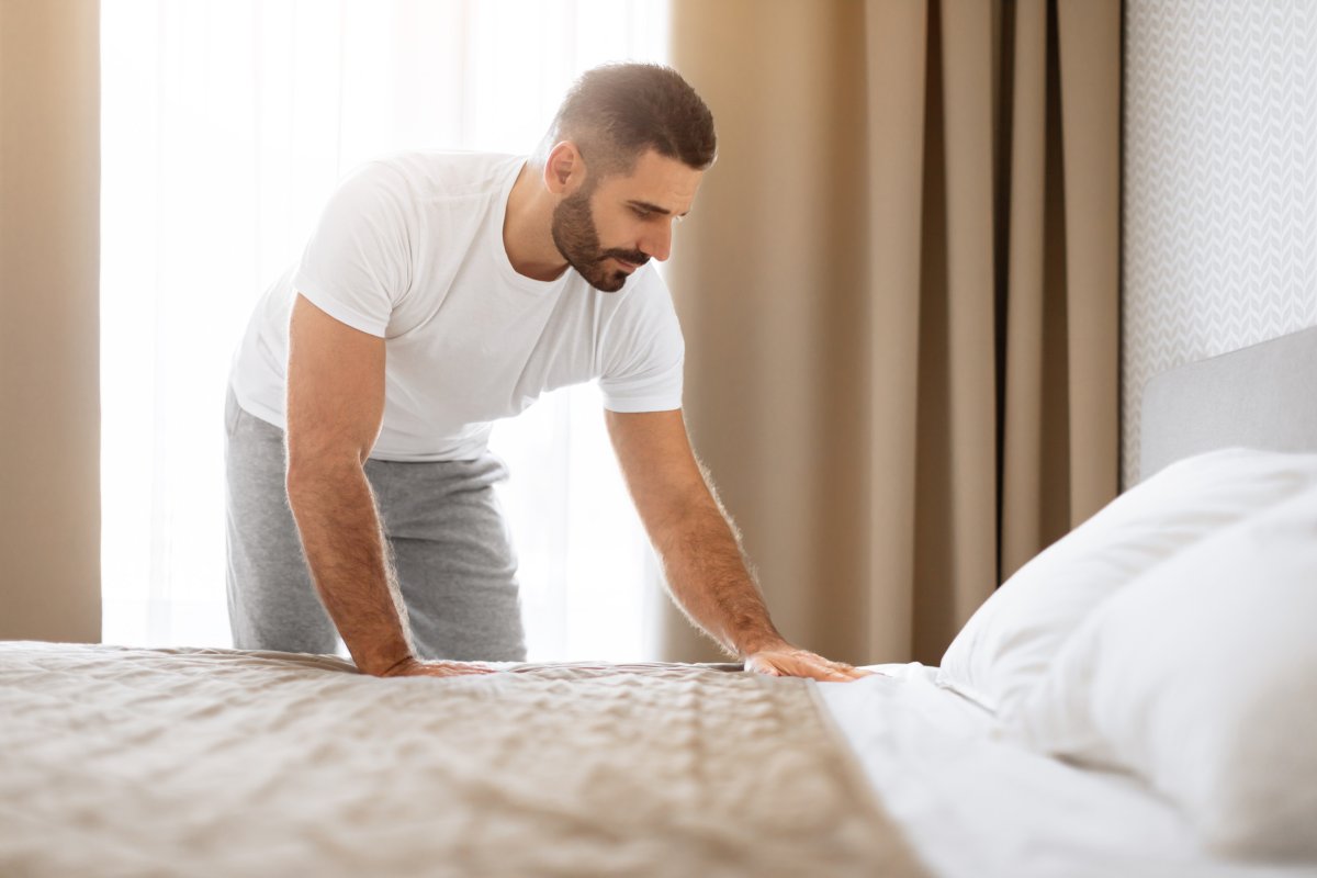 Man making bed in home.