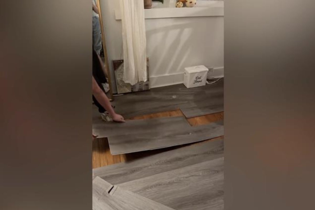 Man pulling up grey floors in home.