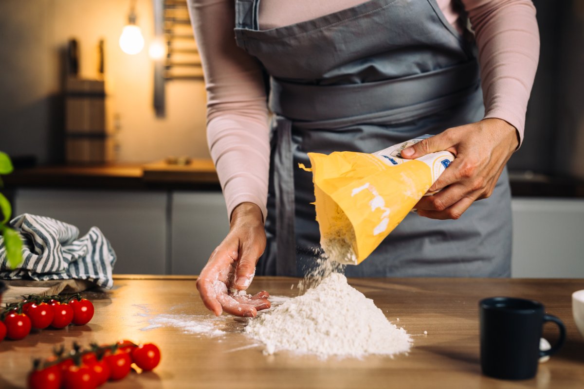 Person pouring flour out on kitchen counter.