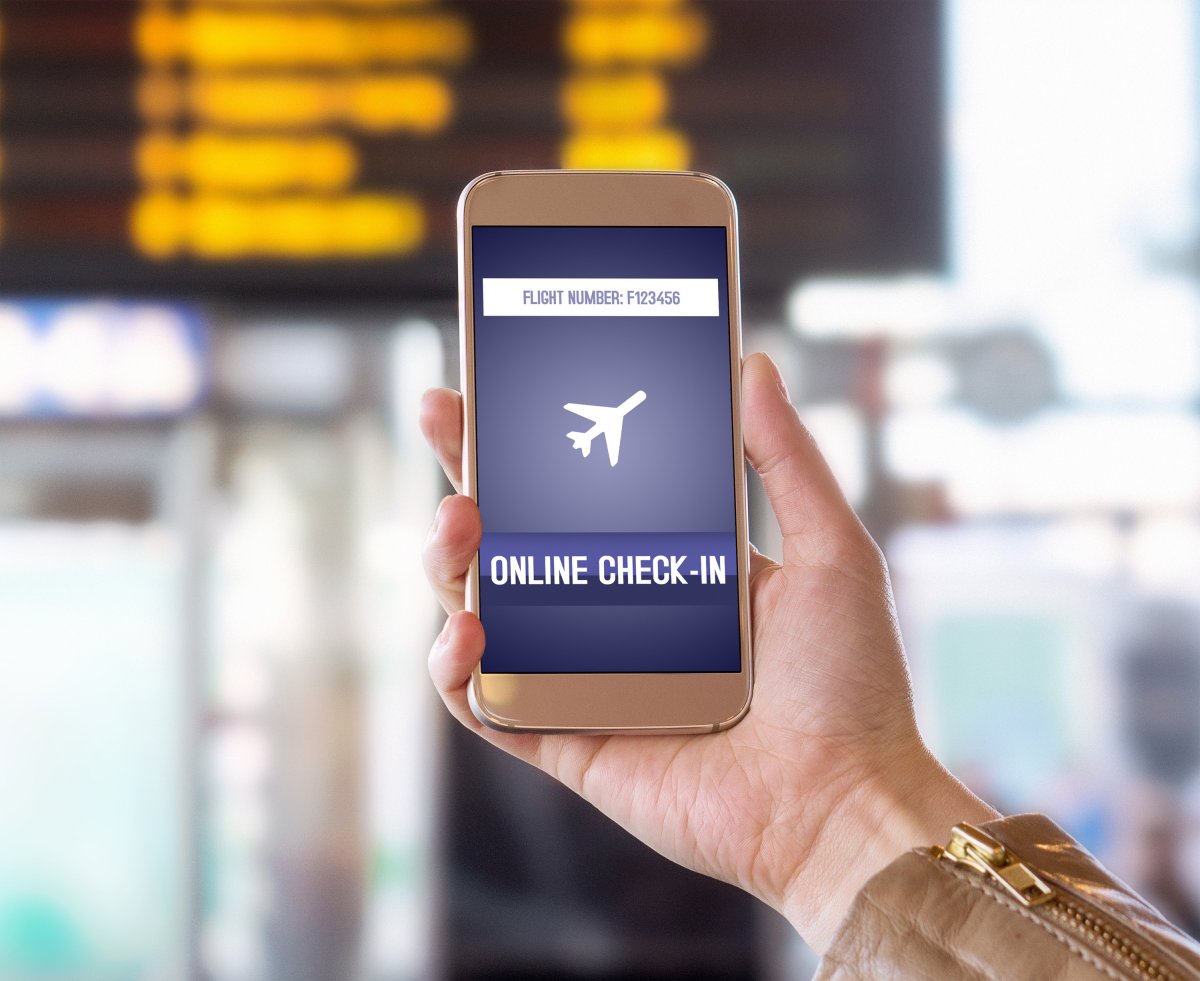 Hand holding up mobile phone in airport.