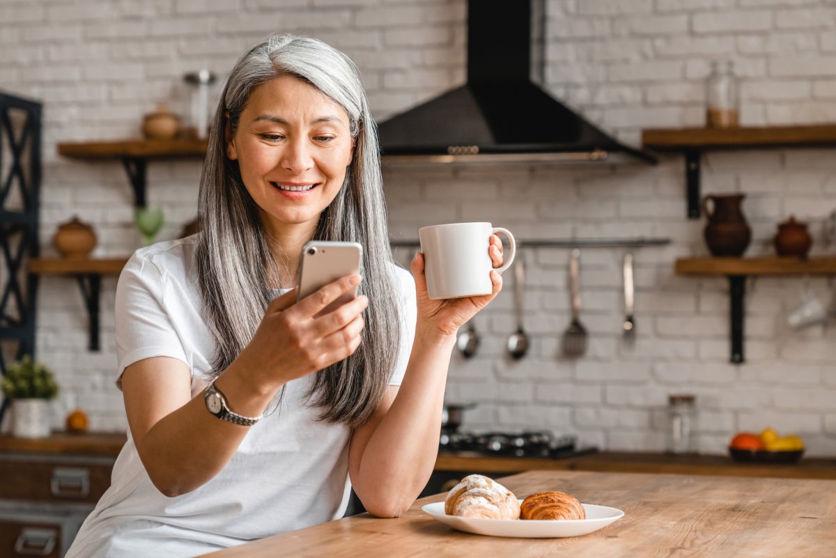 Woman Holding Cell Phone, Coffee in Kitchen