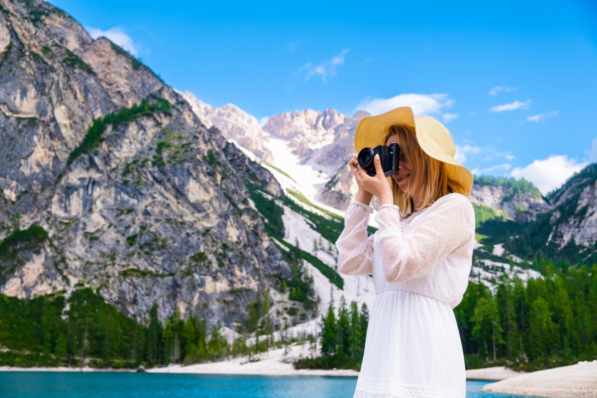 Woman taking picture in scenic mountain setting. 